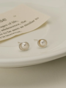 Detailed macro view of S925 silver shell-shaped earrings with lustrous freshwater pearls