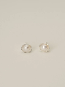 Detailed macro view of silver fan-shaped shell earrings with lustrous white pearls