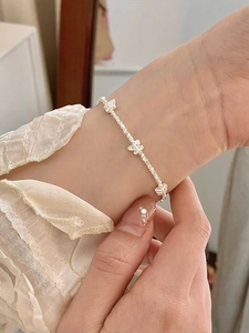 Detailed shot of an S925 silver beaded bow bracelet worn on a lace sleeve wrist