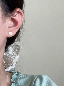 Close-up of a model wearing the fan-shaped silver stud earring with white pearl