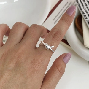 Detailed view of an S925 sterling silver knot ring worn on a hand for a minimalist look