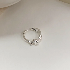 Detailed macro shot of an adjustable S925 silver knot ring on a minimalist background