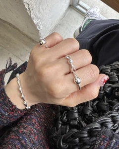 Detailed close-up of polished silver knotted ring and beaded ring styled on hand