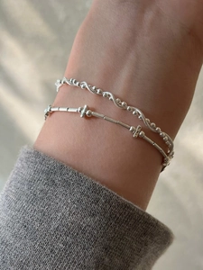 Detail of layered S925 sterling silver bracelets featuring snake and twisted bead chains