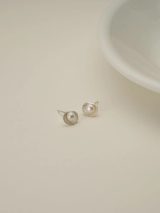 Detailed view of silver shell stud earrings with white freshwater pearls and textured edges