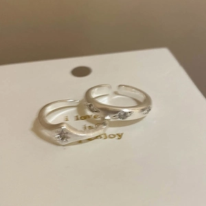 Close-up of silver adjustable rings featuring starburst engraving and zircon inlay detail