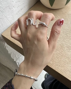Detail view of S925 silver knot ring and letter band with polished bone bracelet