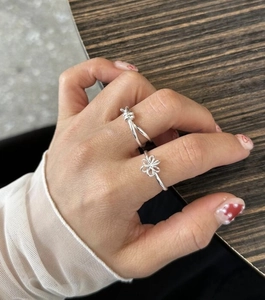 Close-up of S925 silver knot ring and hollow flower design on a woman's hand