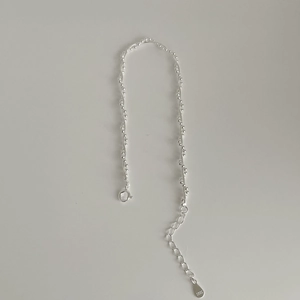 Macro detail of S925 sterling silver tag and beads on a double-layer woven bracelet