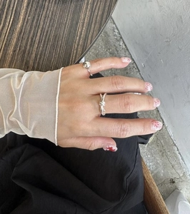 Detail of silver knot ring and beaded wraparound band worn on model hand in natural setting