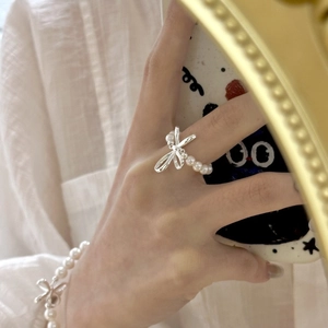 Detailed view of silver bow-shaped pearl ring and matching bracelet on hand