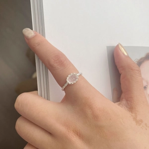 Detail of S925 silver geometric ring with oval gemstone worn on finger over magazine