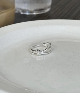Detailed view of a silver knot ring in a minimalist style on a white ceramic plate