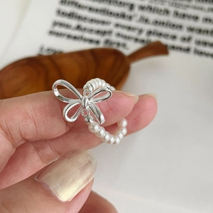 Detail shot of a sweet bow ring with tiny round pearls on a silver band shown on hand