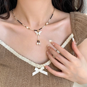 Detail of S925 silver beaded necklace featuring a white butterfly pendant and pearl tassels