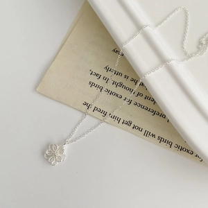 Macro view showing the hollow flower pendant and thin silver chain on aesthetic background