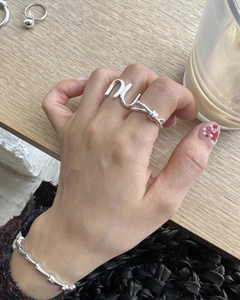 Macro shot of silver minimalist knot double-finger ring on a model with beaded bracelet