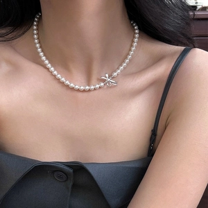 Elegant white pearl necklace with a silver 3D bow pendant on a model's neck