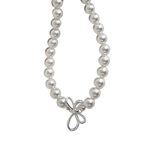 Elegant white pearl necklace with a silver 3D bow pendant on a soft grey background
