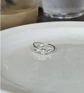 Detailed view of an S925 sterling silver knot ring with twisted rope design on white ceramic