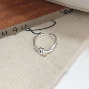 Macro shot of silver minimalist double-layer knotted ring on rustic linen fabric