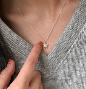 Detail view of a hollow five-petal floral pendant on a S925 silver necklace chain
