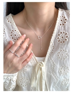 Close-up of S925 sterling silver interlocking ring necklace and wavy rings on model