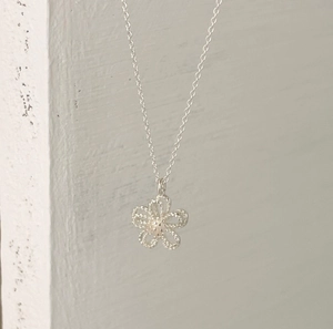 Detail showing an intricate hollow floral pendant with fine woven silver mesh texture