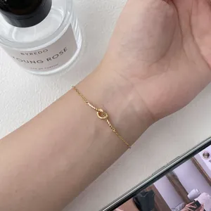 Detailed close-up of a French style twisted knot gold bracelet on a textured surface