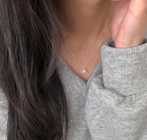 Close-up of S925 sterling silver hollow flower pendant necklace worn on a gray sweater
