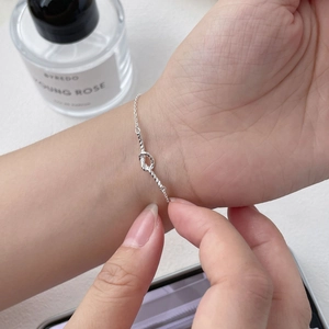 Close-up of minimalist S925 silver knot bracelet worn on wrist with delicate chain