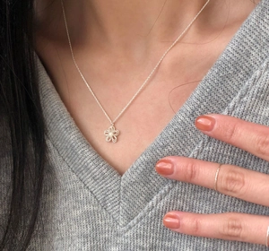 Close-up of S925 silver necklace with hollow flower pendant on a v-neck knitted sweater