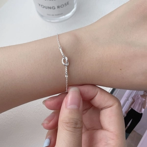 Detail shot of a minimalist S925 silver braided knot bracelet on a woman's wrist