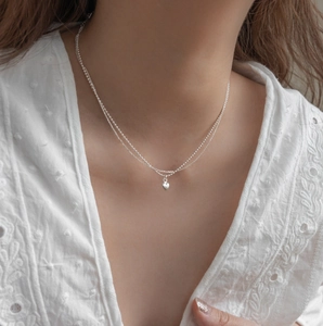 Close-up of double-layer silver heart necklace on a model wearing white lace shirt