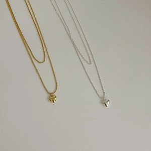 Detail of layered gold and silver necklaces with polished heart-shaped pendants