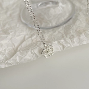 Macro detail of silver S925 geometric hollow flower pendant with beaded texture finish