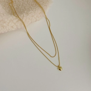 Detailed view of gold double-layered necklace featuring a polished heart-shaped pendant