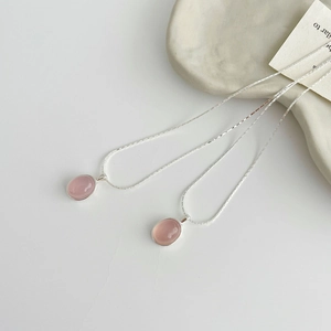 Detail shot of a S925 sterling silver necklace with oval pink chalcedony pendant on marble