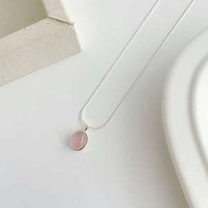 Close-up of S925 silver necklace with an oval pink chalcedony stone on white background