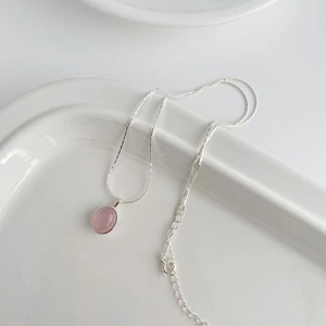 Macro detail of S925 sterling silver chain with pink chalcedony oval pendant on white plate