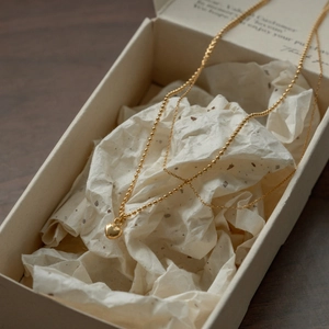 Detail shot of a double-layered gold heart pendant necklace in a luxury gift box