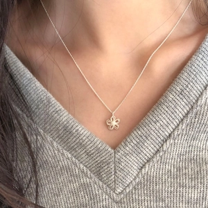 Minimalist S925 silver double-layer hollow flower pendant necklace worn on a V-neck sweater