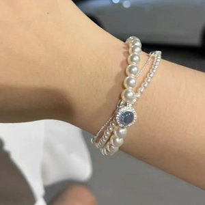 Detail of elegant S925 sterling silver double-layer bracelet with pearls and a blue stone