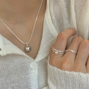 Detail von geschichteten Silberringen und Perlenband kombiniert mit Perlenkette