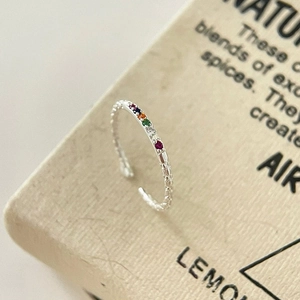 Detailed close-up of S925 silver rainbow zircon ring with colorful gems on paper box