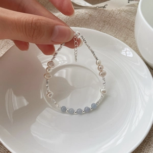 Detail of handmade bracelet with freshwater pearls, blue beads and silver accents