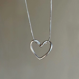 Makroaufnahme des polierten S925 Sterlingsilber Herzanhängers an einer feinen Schlangenkette