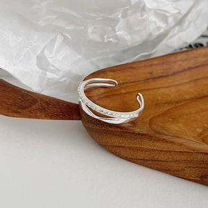 Detail of minimalist double-layered silver ring with white zircon pave on wooden spoon