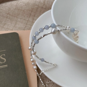 Detail of silver beads and baroque pearls on a minimalist bracelet with extension chain