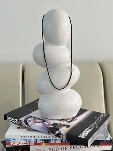 Detail of minimalist black spinel beaded necklace draped over a white ceramic base
